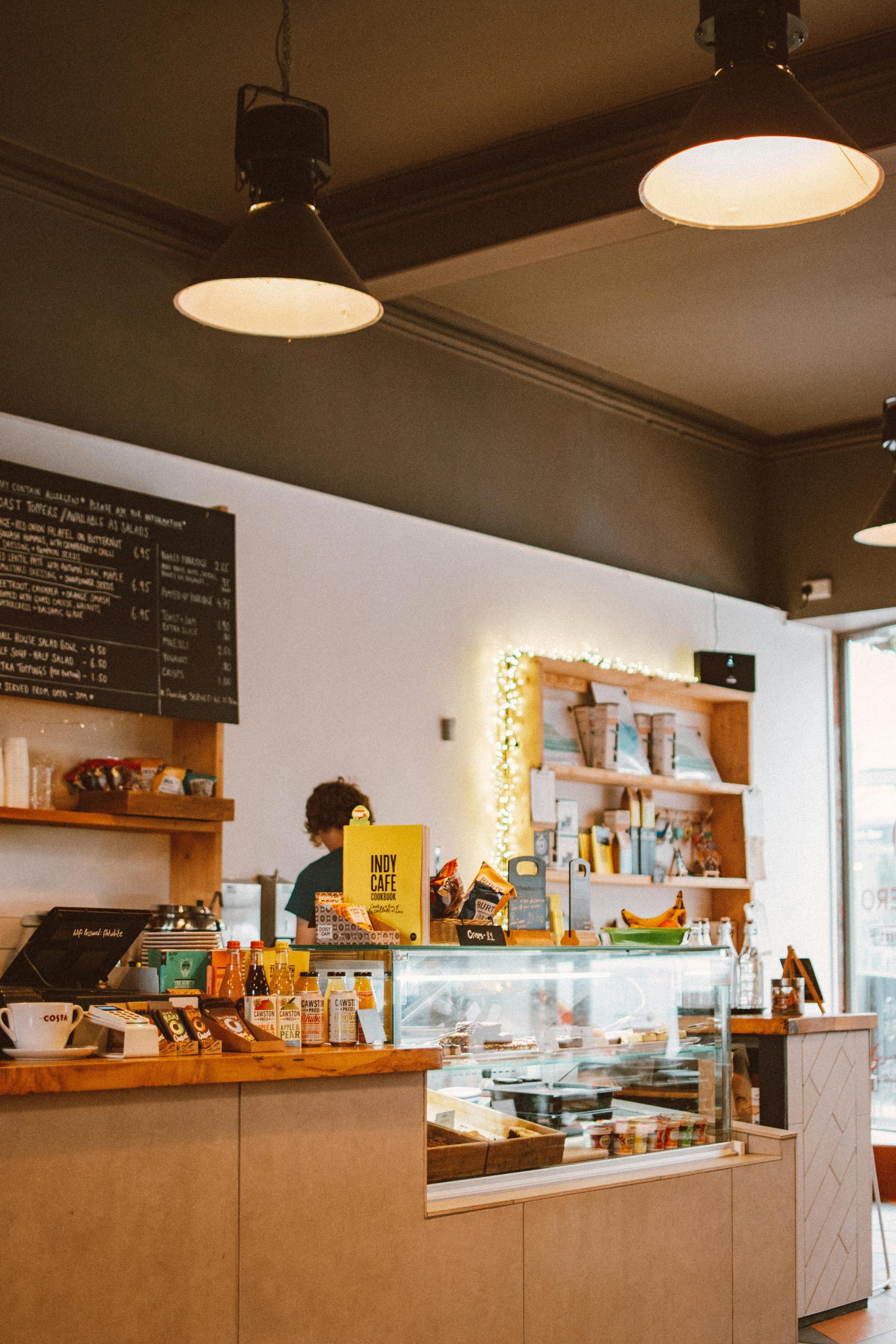 Warm and inviting café interior featuring a counter, displayed menu board, and various food items.