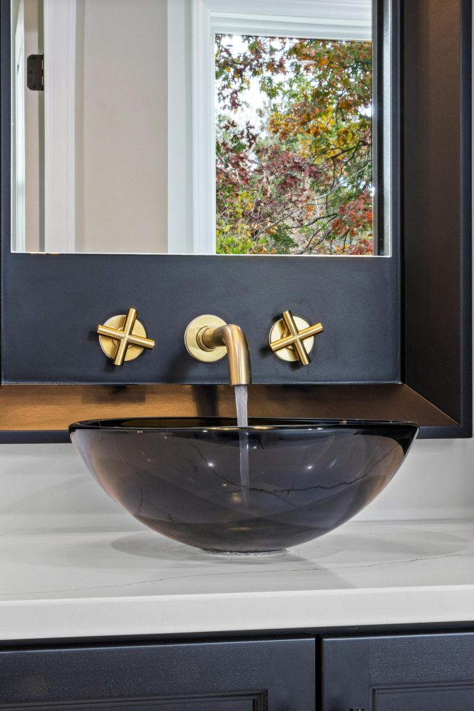 Contemporary bathroom sink setup with gold fixtures and a sleek mirror in a modern interior.